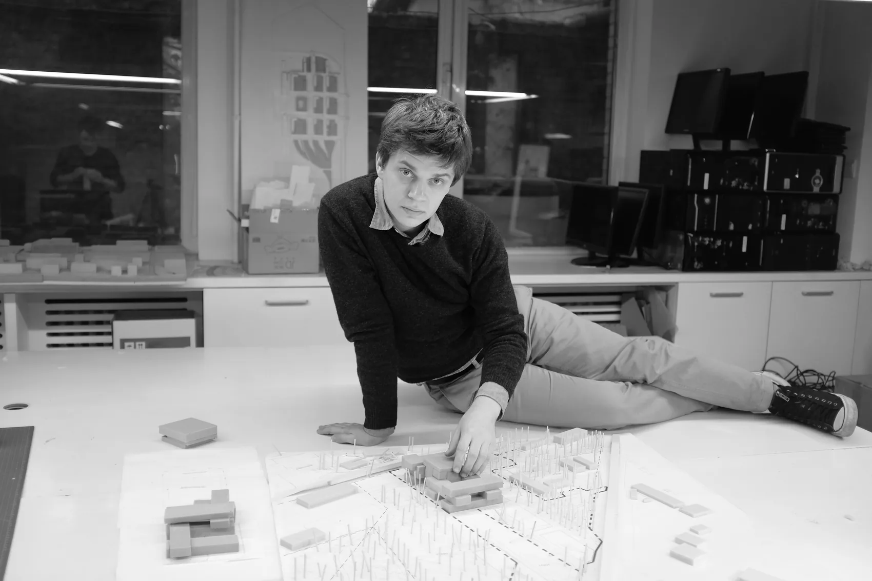 Tomasz lying on the model table, adjusting a massing model
